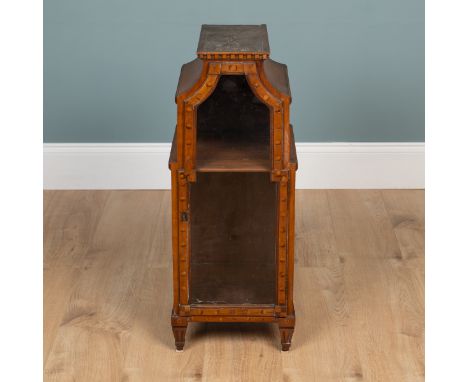 An early 20th century walnut icon cupboard The shaped top with a dentil cornice and decorative inlay, the door with a glazed 