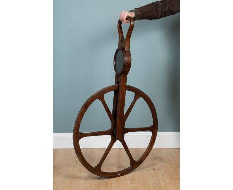 A George III mahogany waywiser  The spoked wheel has an iron tyre beneath a stirrup-type handle and an engraved brass dial si