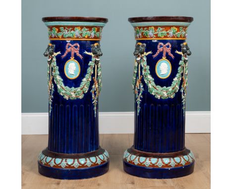 A pair of Wedgwood majolica jardinière stands With moulded polychrome decoration of fruiting swags held by jaguar masks enclo