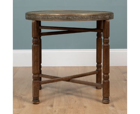 An Indian circular brass tray topped occasional table The top on a folding X-framed hardwood base.60cm diameter x 58cm highQt
