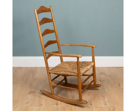 An Arts & Crafts-style oak-framed rocking chair  With a ladder back and shaped arms above a wicker seat.   54cm wide x 109cm 