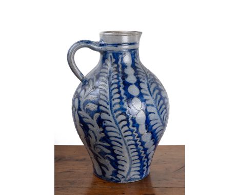 A large German stoneware pitcher or jug In the Westerwald style, decorated with trailing foliage and with a looping handle. A