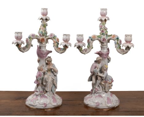A pair of Continental porcelain candelabra Each with three flower-decorated branches. One with a gentleman beneath, the other