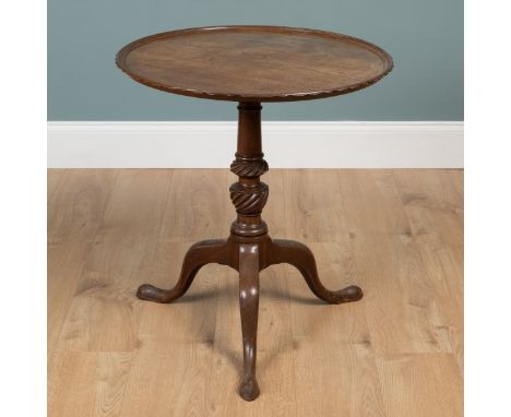 A George III mahogany tilt-top tripod table The circular top with a shaped edge, twisting carving to the cup and cover suppor