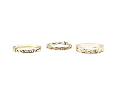 Two modern 9ct gold bangles the first of bi-coloured hinged design, with Roman numeral detail; the second of hinged design, w