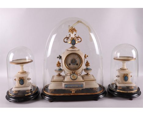 A three-piece alabaster pendulum set under cloches, 2nd half 19th century. The mantel clock crowned with a flower vase, dial 