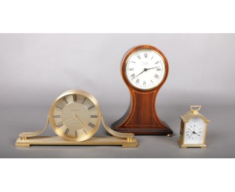 A collection of three clocks - comprising of a 'Churchill' Quartz brass mantle clock, a 'Comitti' of London Mahogany balloon 