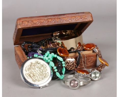 A wooden carved jewellery box. Including a collection of costume jewellery, beads, necklaces, quartz wristwatches, compact ex