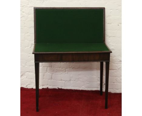 A Georgian mahogany fold over card table raised on tapering supports.