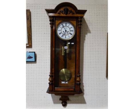 A Walnut Encased Twin Weight Pendulum Wall Clock With Circular White Enamel Dial