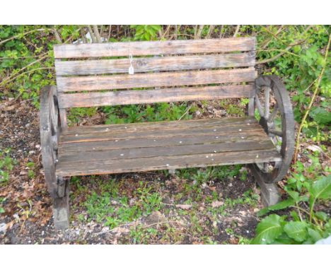 A WOODEN SLATTED CART WHEEL GARDEN BENCH width 113cm ( cart wheels have no age)