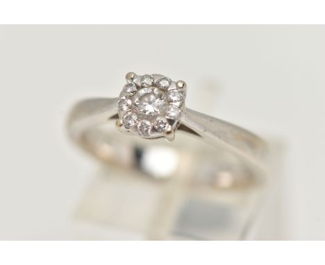 A WHITE METAL DIAMOND CLUSTER RING, centrally set with a round brilliant cut diamond, in a surround of nine smaller round bri