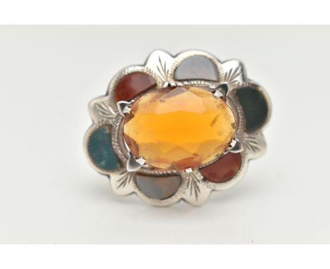 A WHITE METAL HARDSTONE SCOTTISH BROOCH, of an oval wavy form, set with a large oval cut orange paste to the centre, in a sur