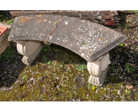A WEATHERED COMPOSITE CURVED GARDEN BENCH with lion head motifs to each base 123cm long (condition report: no visible cracks)