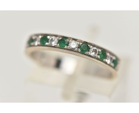 A WHITE METAL EMERALD AND DIAMOND HALF ETERNITY RING, set with seven circular cut emeralds, interspaced with six round brilli