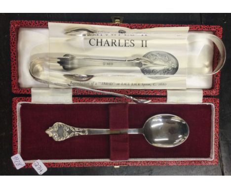 A cased silver collectors spoon together with two pairs of tongs. Approx. 83 grams. Est. £30 - £40.