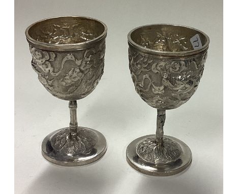 A pair of chased Chinese silver egg cups. Approx. 79 grams. Est. £80 - £120.