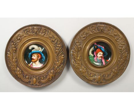 A PAIR OF EMBOSSED CIRCULAR BRASS PLAQUES, inset with porcelain panel decorated with portrait busts. 12.5ins diameter.