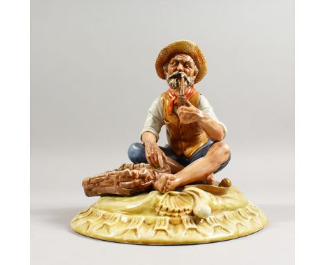 A CAPODIMONTE GROUP, a man seated by a basket of fish, smoking his pipe. 9ins wide.