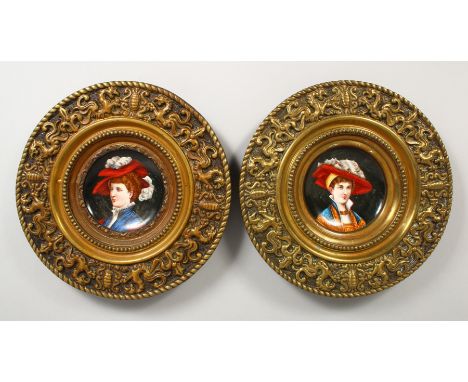 A PAIR OF EMBOSSED CIRCULAR BRASS PLAQUES, inset with porcelain panel decorated with portrait busts. 12ins diameter.