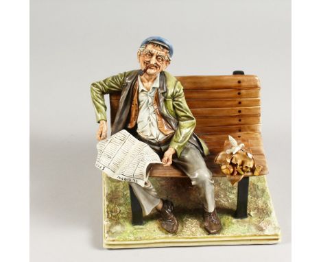 A CAPODIMONTE GROUP, a man seated on a bench, smoking a pipe and reading a newspaper. 9ins wide.