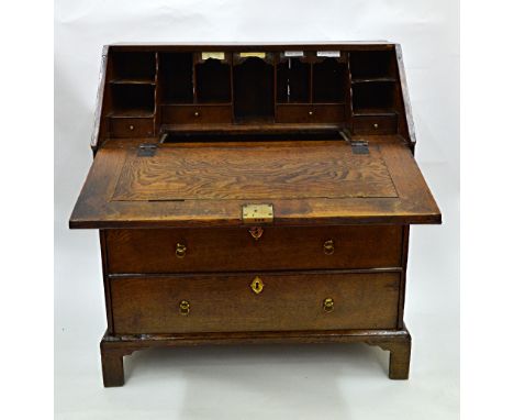 A George I oak bureau, the hinged fall enclosing a stepped fitted interior around a well with sliding cover, two short and tw