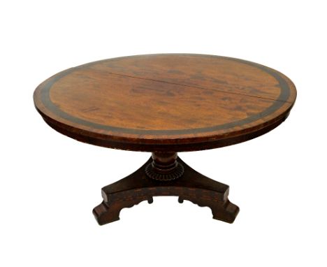 A George IV mahogany breakfast table, the circular tilt-top with a wide black palmwood banding, the frieze and concave sided 