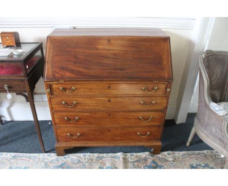 A George III mahogany bureau, the hinged fall enclosing a boxwood strung central cupboard flanked by small drawers and pigeon