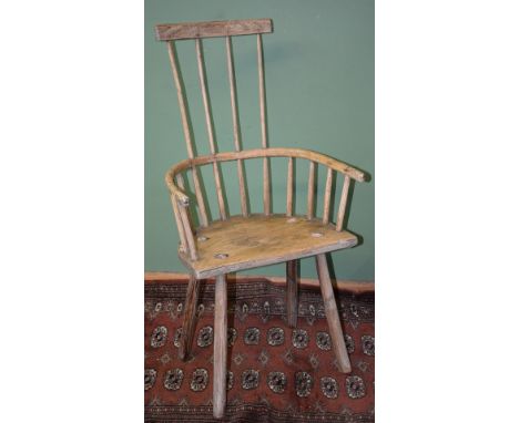 A rustic Ash and other woods comb back Armchair having a 'D' shaped seat, curved arm rests and angled primitive spoke shaven 