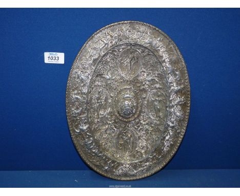 A heavy oval metal Plaque, highly decorated in relief with depictions of hunting scenes to the rim and four panels of figures