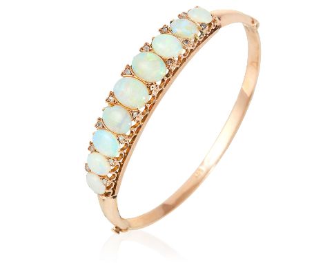 AN ANTIQUE OPAL AND DIAMOND BANGLE in yellow gold, set with a row of nine graduated oval opal cabochons accented by rose cut 