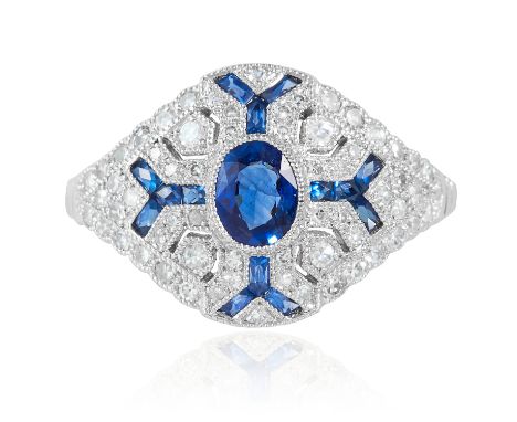 AN ART DECO SAPPHIRE AND DIAMOND RING in platinum or white gold, the oval cut sapphire within a geometric surround of round c