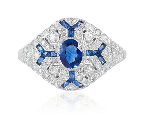 AN ART DECO SAPPHIRE AND DIAMOND RING in platinum or white gold, the oval cut sapphire within a geometric surround of round c