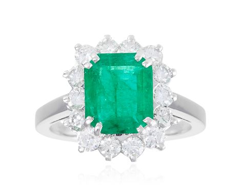 AN EMERALD AND DIAMOND CLUSTER RING in white gold or platinum, set with an emerald cut emerald in round cut diamonds, marked 