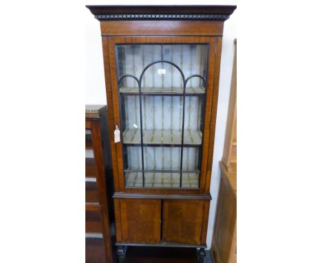 An Edwardian mahogany tall and narrow display cabinet with astragal glazed door and cupboard base with undertier, 68cm wide, 