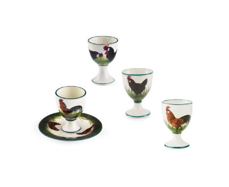   FOUR 'COCKEREL AND HENS' EGGCUPS to include a 'BROWN COCKEREL AND HENS' EGG CUP AND SAUCER, glazed earthenware, painted and