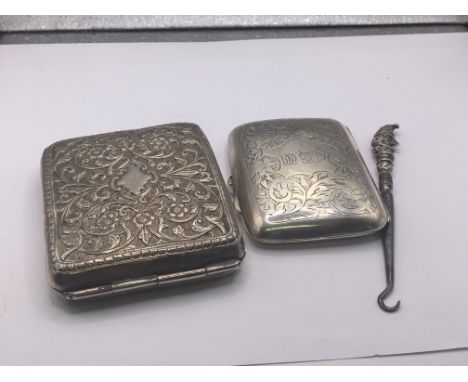 A silver cased cigarette box. Birmingham hallmarks a Mr Punch silver topped button hook and a large unmarked white metal ciga