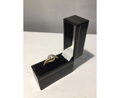 A 9 CARAT GOLD RING WITH A CLEAR STONE SOLITAIRE AND CLEAR STONES ON THE SHOULDERS WITH PRESENTATION BOX 