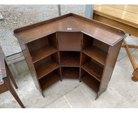 AN EARLY 20TH CENTURY OAK CORNER OPEN BOOKCASE WITH CENTRAL DOOR ENCLOSING PIPE RACK 