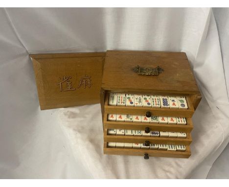 A VINTAGE MAHJONG SET IN AN OAK CASE WITH SLIDE DOOR AND FIVE FITTED DRAWERS - COMPLETE WITH 144 TILES PLUS A SPARE, RULE BOO