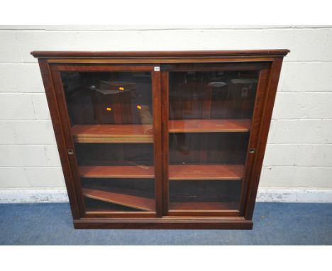 AN EARLY 20TH CENTURY MAHOGANY BOOKCASE, with double glass sliding doors, enclosing an arrangement of shelves, width 152cm x 