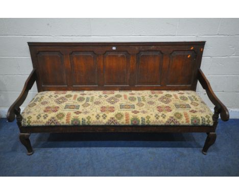 A GEORGIAN OAK SOFA, the backrest with five panels, scrolled open armrests, the upholstery with repeating geometric patterns,