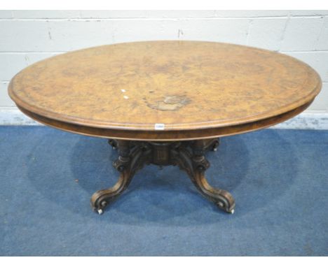 A VICTORIAN BURR WALNUT TILT TOP OVAL LOO TABLE, raised on four turned supports, scrolled and foliate legs, with ceramic cast