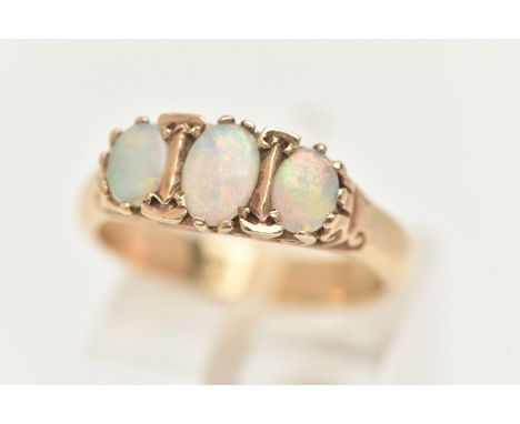A THREE STONE OPAL RING, three oval opals prong set in yellow metal, scroll detail to the shoulders, unmarked, ring size N, a