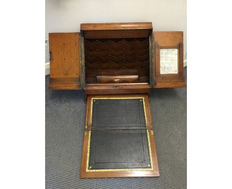 A Victorian oak stationery box with two doors opening to reveal a pigeonholed interior with pen tray and fold-out compartment