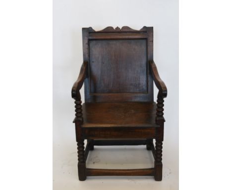 An oak wainscot chair with panelled back and shaped arms, on bobbin turned supports, solid seat on bobbin turned legs and fla