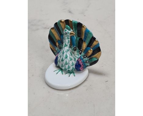 A Herend hand painted Peacock raised on white oval base, 2"High and bearing blue mark to base.
