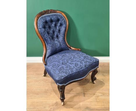 A Victorian spoon back Nursing Chair with blue button upholstery on cabriole front legs and casters