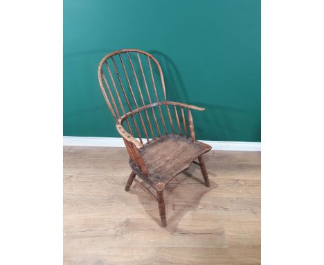 A 19th Century primitive ash hoop back Elbow Chair with stick back and shaped seat raised on turned supports united by H-stre