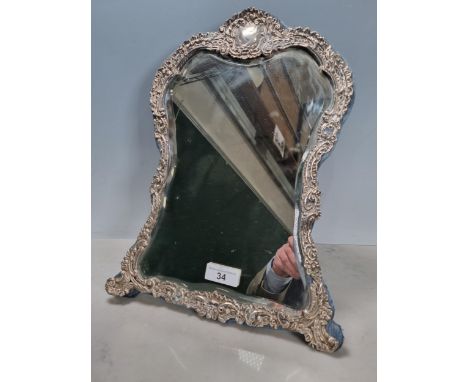 A George V silver framed Easel Mirror with scroll embossed surround, vacant cartouche, Birmingham 1912, worn, 17 x 11in